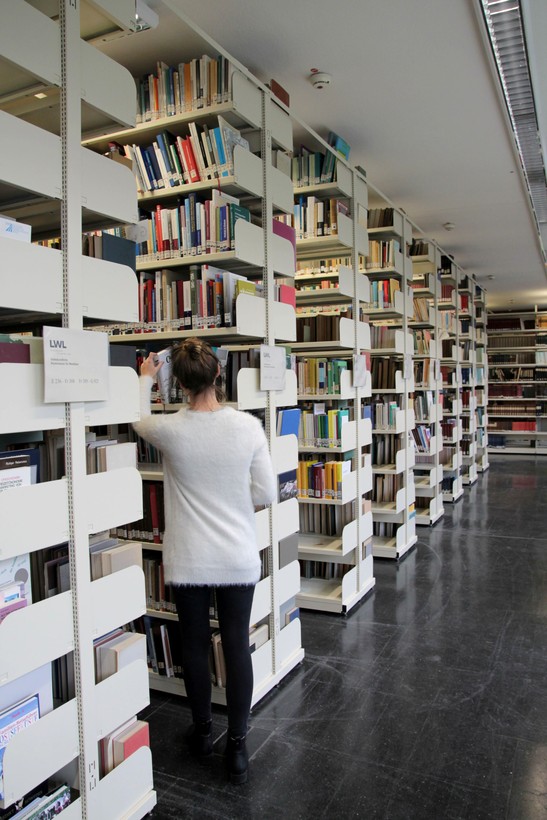 Eine Mitarbeiterin nimmt ein Buch aus einem Regal der Bibliothek der Kommission Alltagskulturforschung. Eine Mitarbeiterin nimmt ein Buch aus einem Regal der Bibliothek der Kommission Alltagskulturforschung.