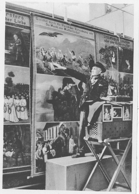 Ein Mann vor großen Tafeln mit zahlreichen Bildern.
