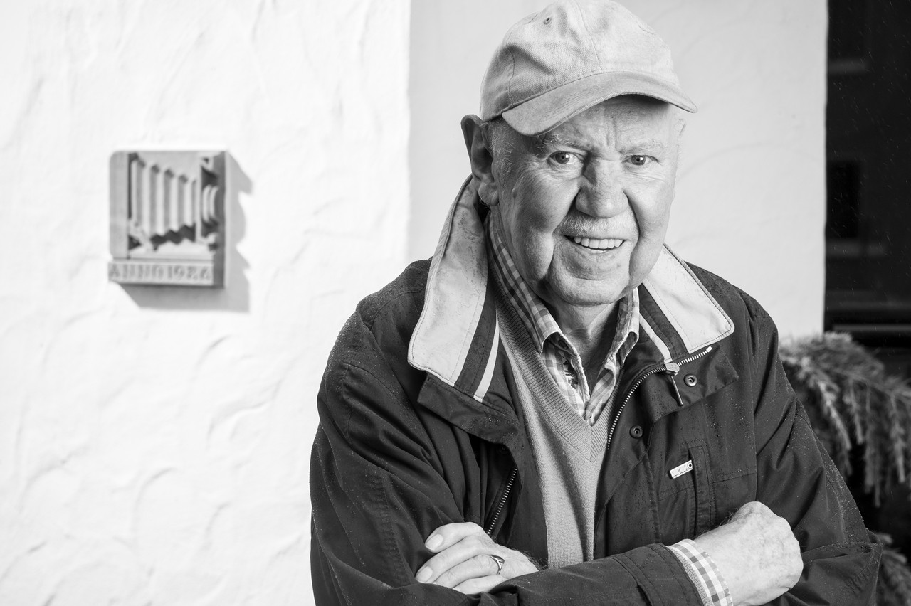 Der Fotograf Helmut Orwat vor dem Grundstein seines Wohnhauses in Castrop-Rauxel (der Grundstein trägt als Motiv eine in Sandstein gehauene historische Balgenkamera), 2022. Foto: Stephan Sagurna, LWL-Medienzentrum für Westfalen