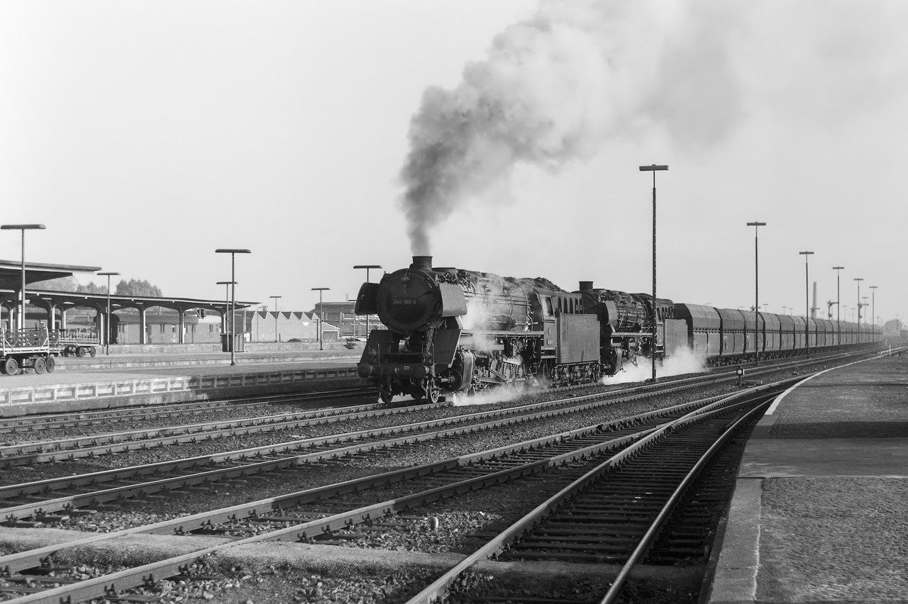 Doppelte Kraft für schwere Last: Die kohlegefeuerte 044 199-8 zieht gemeinsam mit einer ölgefeuerten Schwester der Baureihe 043 einen Erzzug nach Emden. (Rheine, 17.10.1970;  aus dem Dampflokkalender 2024 von Rainer Kohl)