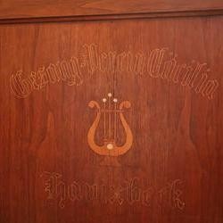 Lyramotiv und Inschrift auf dem Notenschrank. (vergrößerte Bildansicht wird geöffnet)