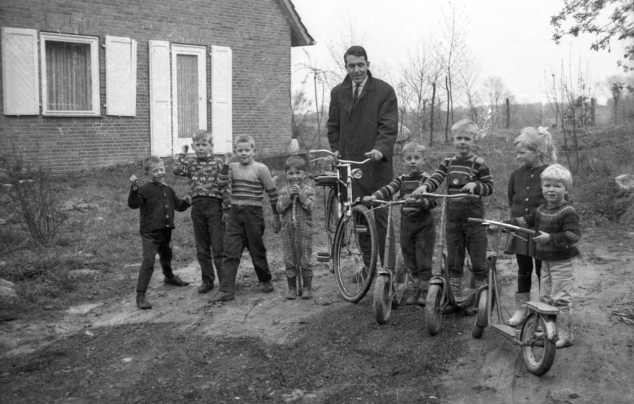 Ein Mann steht zwischen mehreren Kindern, einige von ihnen haben einen Tretroller.