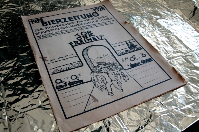 Eine Bierzeitung liegt auf einem goldenen Untergrund.