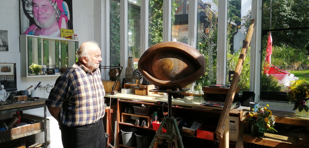 Der Künstler Bruno Buschmann blickt in seinem Oerlinghauser Atelier auf die Skulptur eines Auges. Das Foto ist 2021 entstanden. Foto: Anna Vogt.