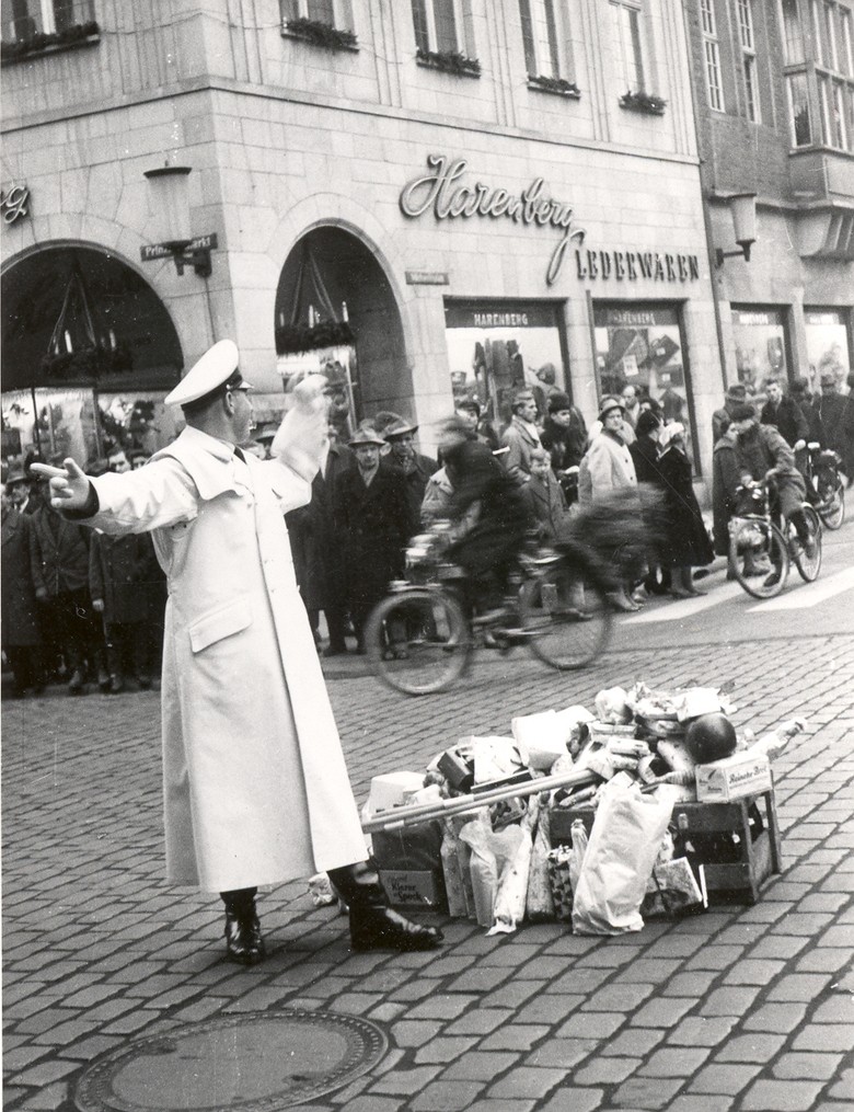 Auf dem Prinzipalmarkt in Münster wurde bis 1968 der Verkehr durch einen Verkehrspolizisten geregelt. In der Vorweihnachtszeit überreichten ihm Autofahrer:innen Geschenke (Münster 1958, Foto: A. Risse, Archiv für Alltagskultur, Sign. 0000.69774).