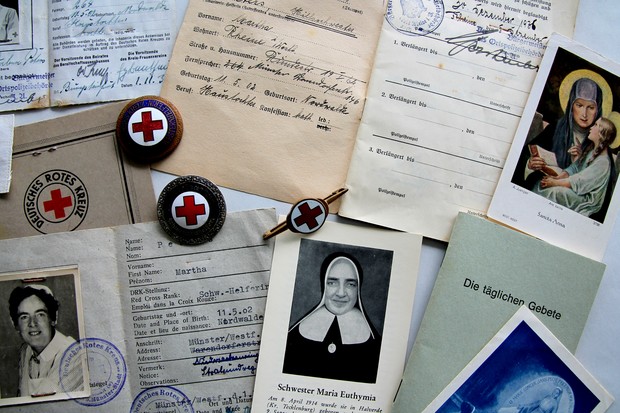 Verschiedene Dokumente einer Schwester des Deutschen Roten Kreuzes, Abzeichen, Bilder einer Heiligen sowie Schwester Euthymia. Archiv für Alltagskur.