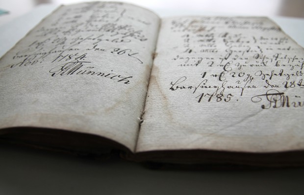 Ein Buch mit handgeschriebenem Text, in dem die Jahreszahl 1785 erkennbar ist. Das Buch sieht sehr alt aus. Archiv für Alltagskultur.